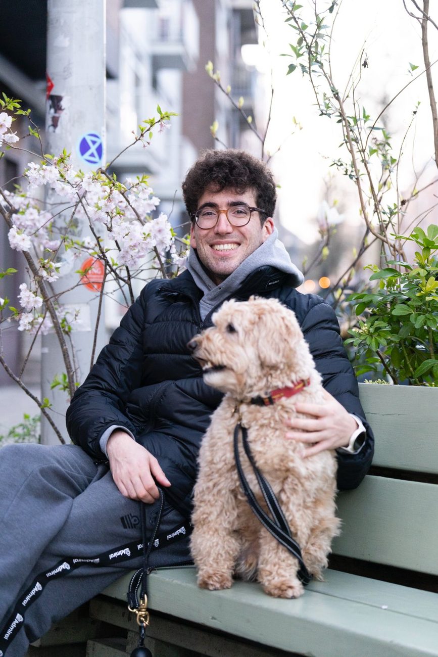 Panos smiling on a bench with Finley the labradoodle on his lap